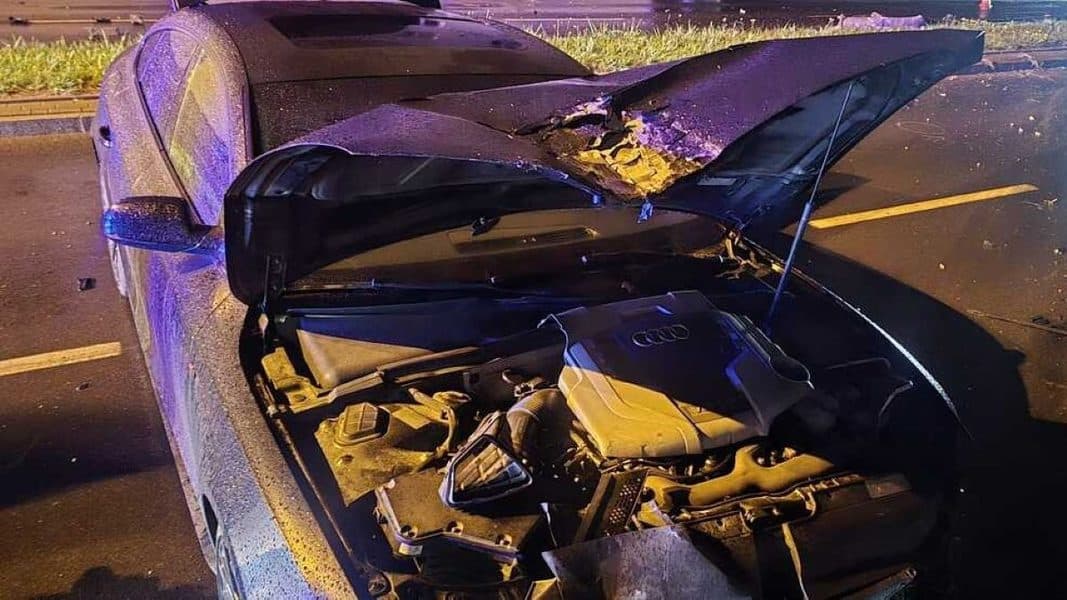 Uszkodzone audi z rozbitym silnikiem i przewróconą latarnią na ulicy w Olsztynie.