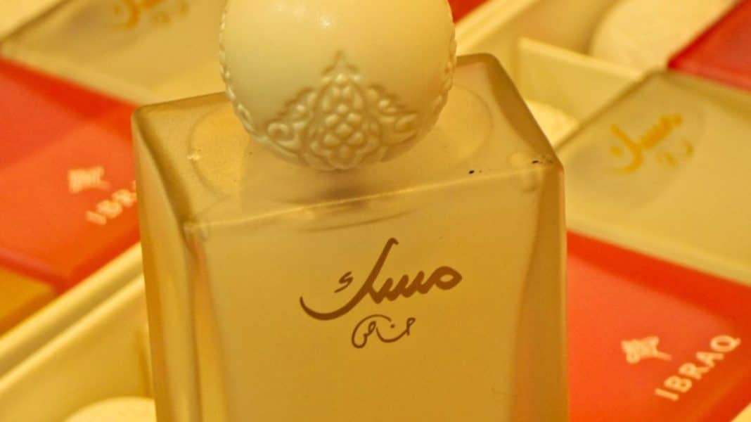 Buteleczka perfum arabskich z ozdobnym korkiem na tle innych perfum w opakowaniach.