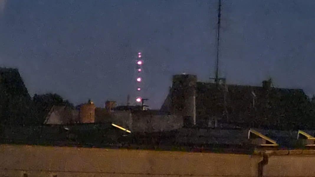 Wieża telewizyjna w Pieczewie z migającymi czerwonymi światłami nocą.