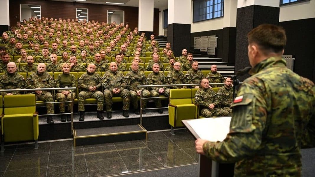 Grupa nowo przyjętych funkcjonariuszy słucha szkolenia w sali wykładowej, z osobą prowadzącą na pierwszym planie.