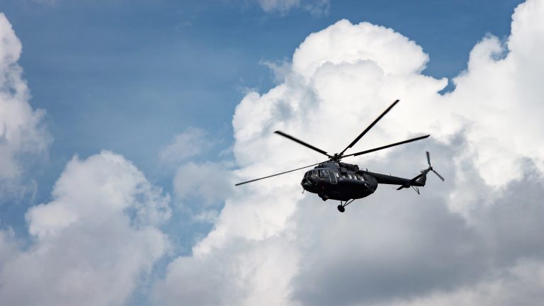 Czarny helikopter Mi-8 w locie na tle chmur na niebie.