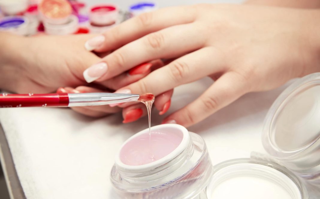Przygotowanie paznokci do nakładania żelu, widoczne narzędzia i produkty do manicure.