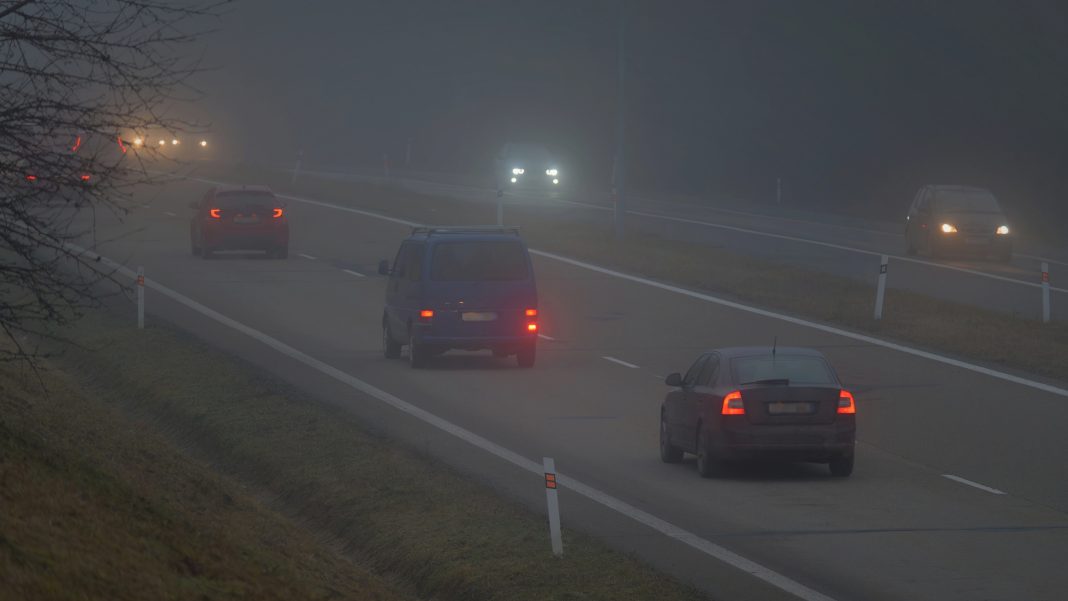 Samochody jadą w gęstej mgle na drodze w regionie warmińsko-mazurskim.