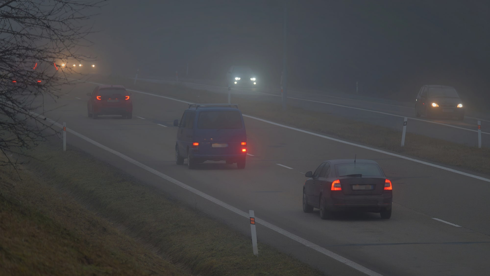 Samochody jadą w gęstej mgle na drodze w regionie warmińsko-mazurskim.