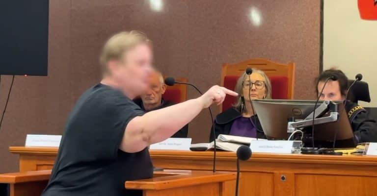 Osoba na sali sądowej przemawia do sędziów, w tle sędzia i inni uczestnicy procesu.