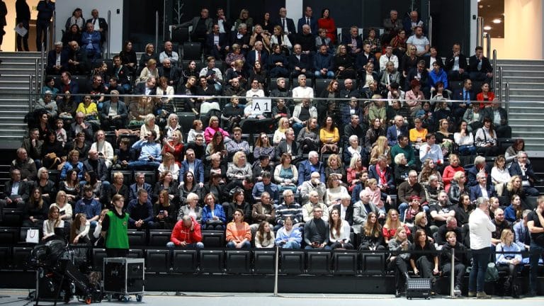 Widok na dużą publiczność siedzącą na trybunach hali Urania podczas wydarzenia sportowego.