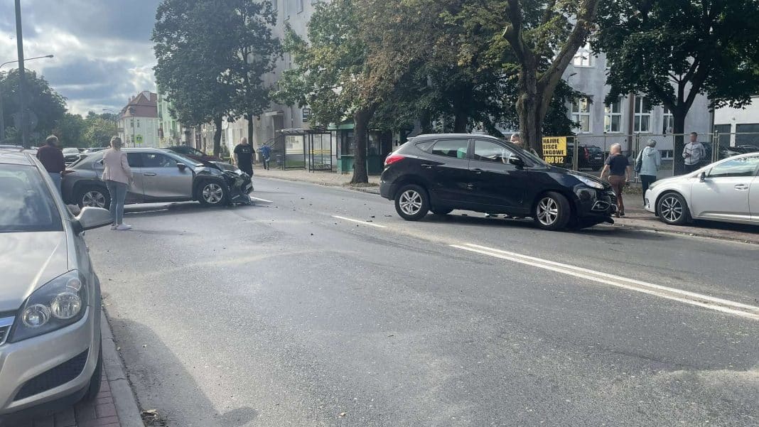 Zderzenie trzech samochodów na skrzyżowaniu w Olsztynie, zablokowana droga, ludzie na miejscu zdarzenia.