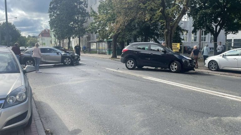 Zderzenie trzech samochodów na skrzyżowaniu w Olsztynie, zablokowana droga, ludzie na miejscu zdarzenia.