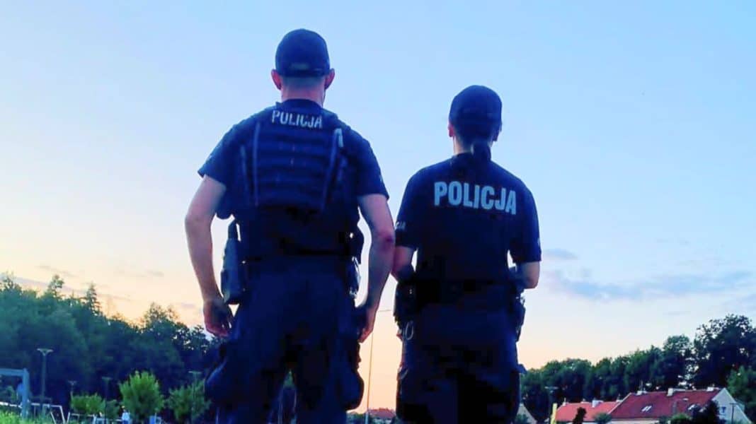 Dwóch policjantów stoi na tle nieba o zmierzchu, patrząc w kierunku miasta.
