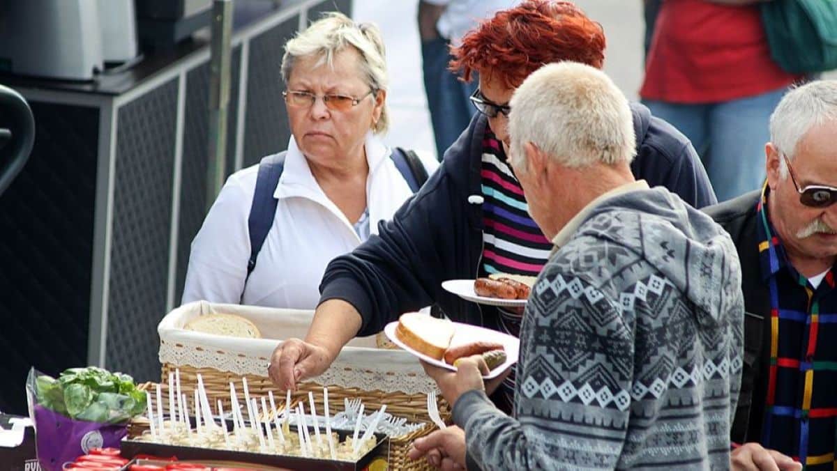 Grupa osób wybiera ser z stołu podczas festiwalu serowego w Kortowie.