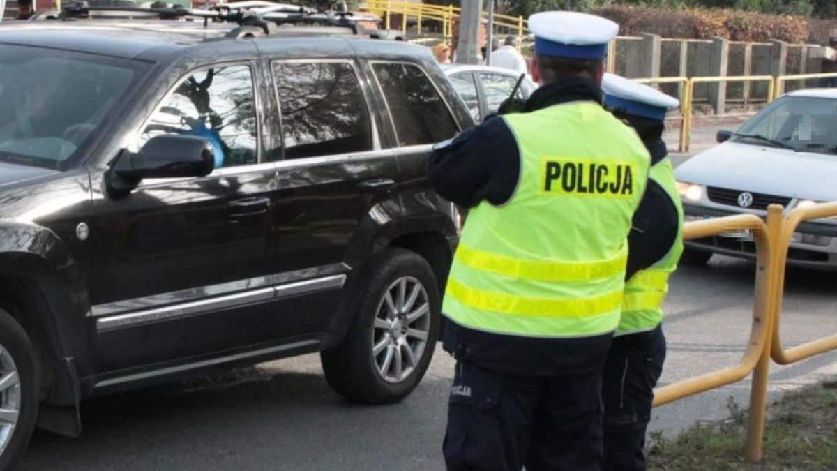 Policjanci na ulicy, w tle samochody i barierki, widać funkcjonariuszy w odblaskowych kamizelkach.