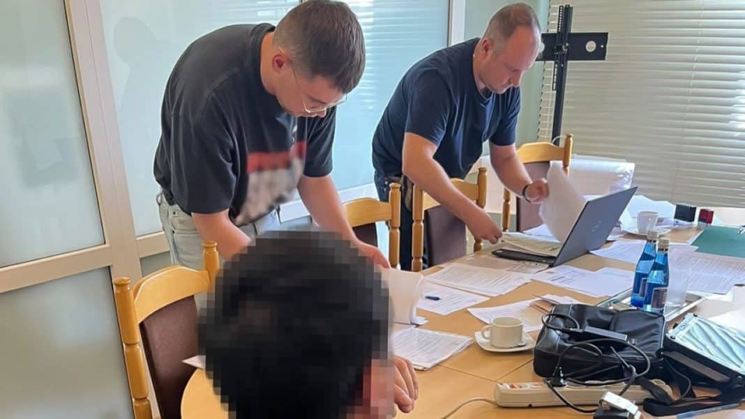 Dwoje mężczyzn przegląda dokumenty na stole w biurze, obok laptop i inne materiały biurowe.