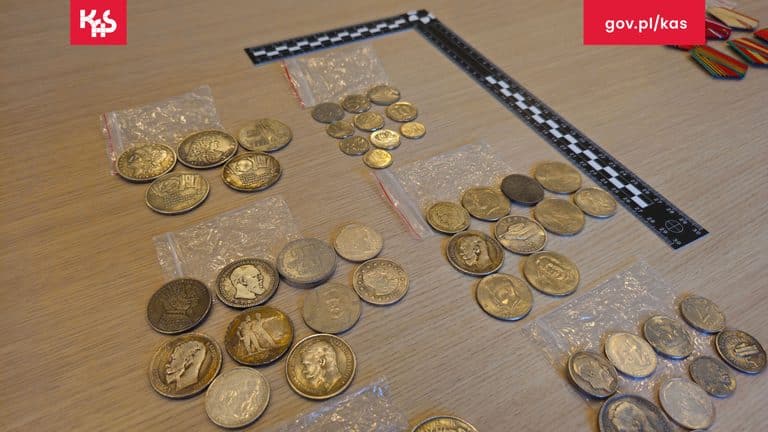 Złote monety i medale rozłożone na stole podczas kontroli granicznej.