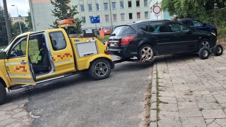 Samochód odholowany przez służby miejskie z chodnika przed szkołą w Olsztynie.