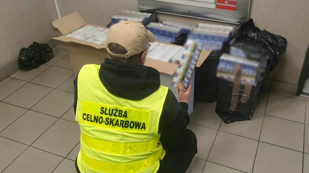 Pracownik służb celno-skarbowych przeszukuje kartony i torby w pomieszczeniu na Mazurach.