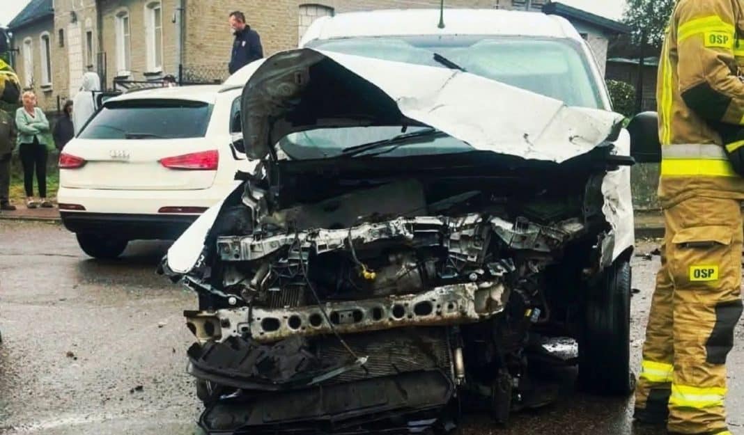 Rozbity samochód po wypadku na ulicy, na miejscu strażacy i świadkowie.