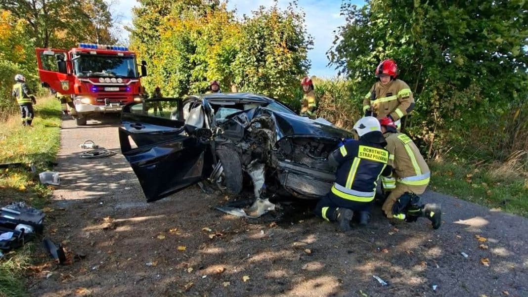 Rozbity samochód osobowy po wypadku na drodze, na miejscu służby ratunkowe, w tym śmigłowiec LPR.