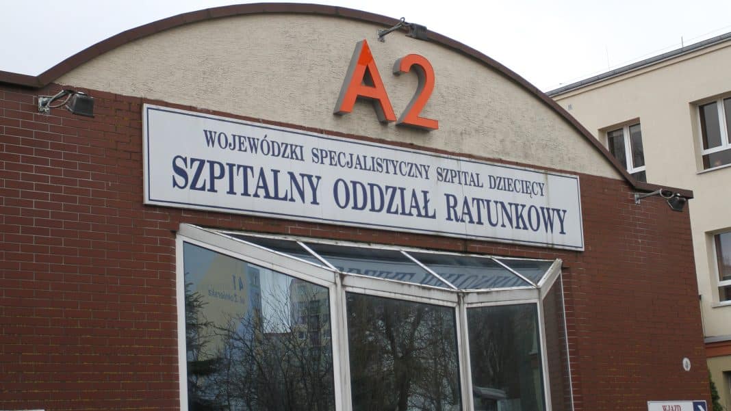 Widok z zewnątrz szpitala dziecięcego w Olsztynie, budynek z tablicą informacyjną.