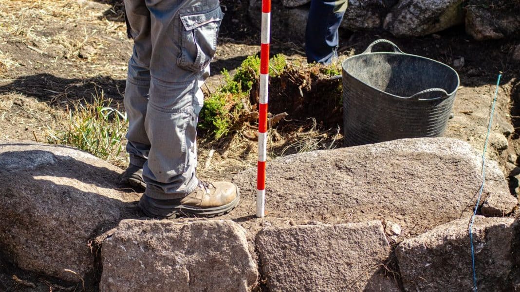 Pracownik archeologiczny bada starożytne kamienie podczas wykopalisk na budowie w Olsztynie.