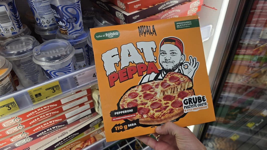 Opakowanie pizzy Książula w sklepie Żabka, widoczne pomarańczowe i zielone kolory, ilustracja twórcy kulinarnego.