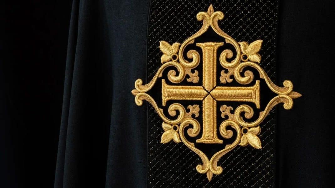 Złocony haft płaski na czarnym materiale, przedstawiający krzyż i ozdobne elementy.