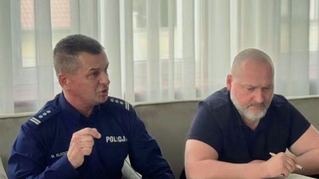 Dwóch mężczyzn w policyjnych uniformach podczas spotkania w pomieszczeniu z dużymi oknami.