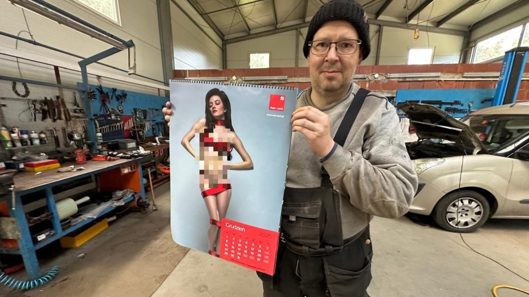 Mężczyzna trzyma kalendarz z modelką, w tle warsztat samochodowy z narzędziami i samochodem.